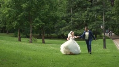 Yürüyüş ve şehir parkında el ele tutuşarak kadın ve iki erkek. Ağır çekim