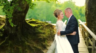 Ormanın içinde askıya alınmış ahşap köprü üzerinde yürüyen aşık genç çift