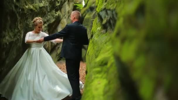 Pareja sobre un fondo de hermosas rocas. Pareja de pie bajo la montaña — Vídeos de Stock