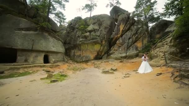 一对在美丽的岩石背景。站在山下的情侣 — 图库视频影像
