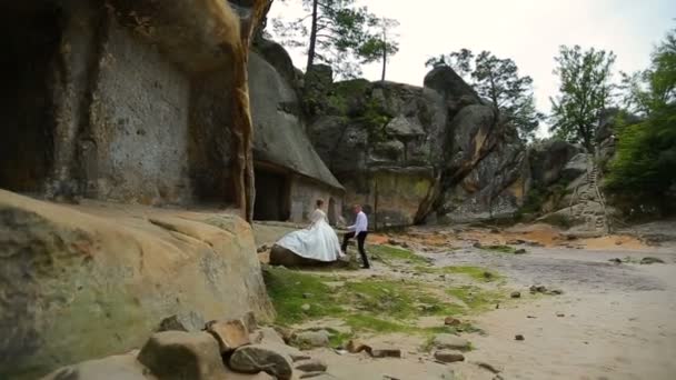 Pareja sobre un fondo de hermosas rocas. Pareja de pie bajo la montaña — Vídeos de Stock