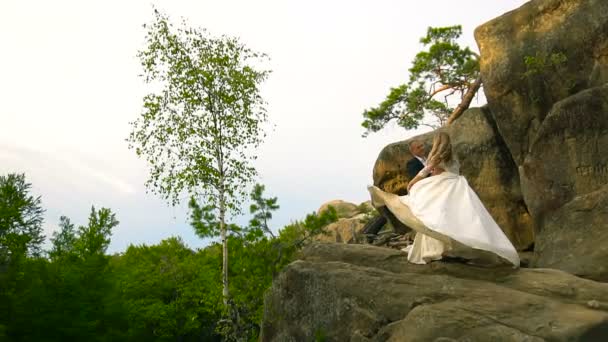 Casal escalando na rocha e admirando o nascer do sol, o pôr do sol. Movimento lento — Vídeo de Stock