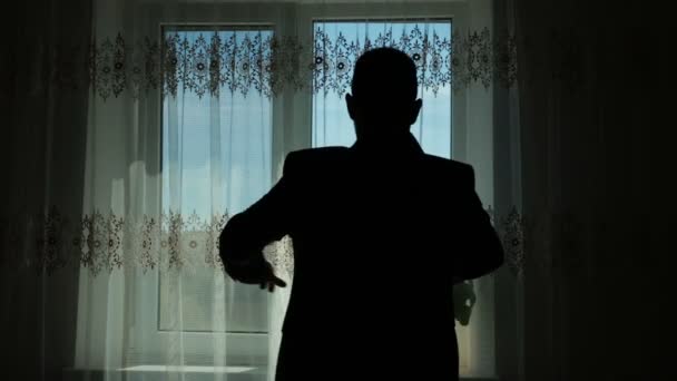 Man draagt een jas voor een venster contrast — Stockvideo