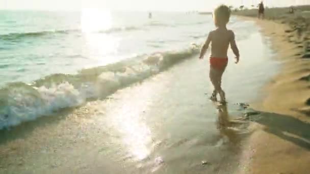 Gyermek meztelen és mezítláb fut végig a tengerparton egy naplemente nyári nap 4k — Stock videók
