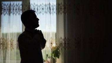 4k Man giyen ve pencere silueti yakınında gömlek düğmeleme