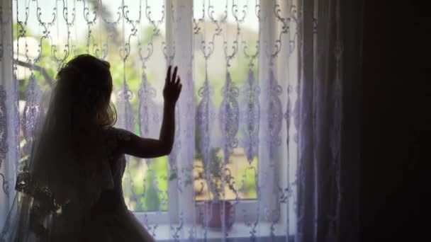 Silueta de mujer desvelando cortinas y mirando por la ventana — Vídeo de stock