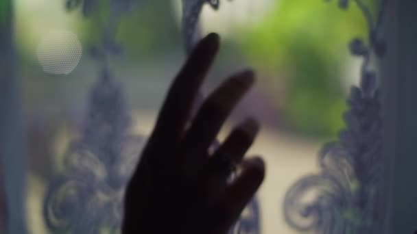 Silueta ženy, která odbíjejí záclony a dívá se z okna — Stock video