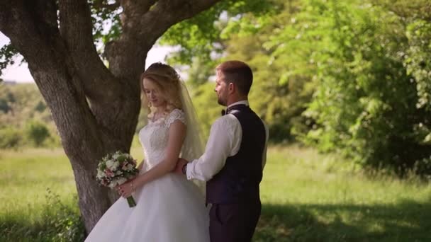 Ženich přichází na kouzelnou blonďatou nevěstu s kyticí za ní. Zpomaleně — Stock video