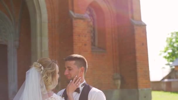 Paar bruid en bruidegom is slenteren in de open lucht over de oude kerk — Stockvideo