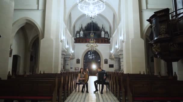 Un par de músicos tocan bandura y acordeón en la iglesia católica — Vídeos de Stock