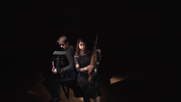 Muzikanten meisje en jongen in een donkere kamer spelen op accordeon en bandoera — Stockvideo