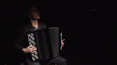Müzisyen karanlık odada akordeon çalan bir şapka giyiyor