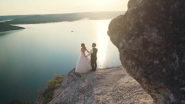 Çift okyanus kayalıklarına doğru yürür, birlikte manzaraya bakar. Yavaş çekim.