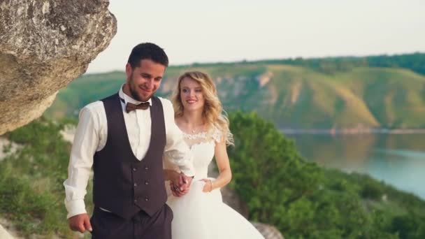 Pareja enamorada de un paseo entre las piedras costeras en la orilla del mar. Movimiento lento — Vídeo de stock