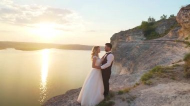 Çift okyanus kayalıklarına doğru yürür, birlikte manzaraya bakar. Yavaş çekim.