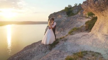 Çift okyanus kayalıklarına doğru yürür, birlikte manzaraya bakar. Yavaş çekim.