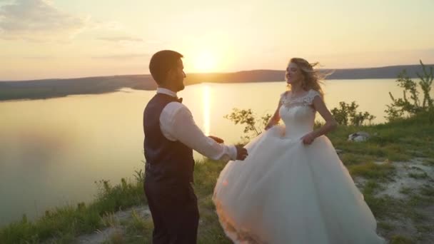 Couple sur la plage au coucher du soleil. La fille saute dans les bras de son petit ami. Mouvement lent — Video