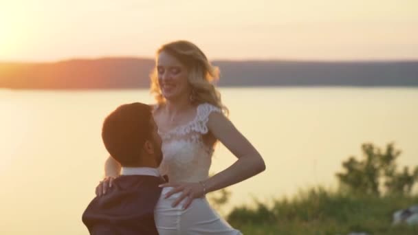 Paar op het strand bij zonsondergang. Meisje springt in haar vriendje armen. Slow Motion — Stockvideo