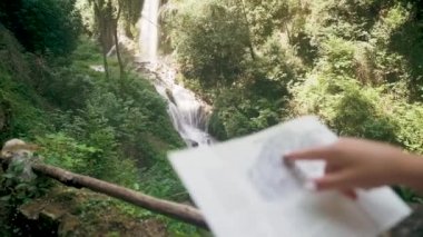 Dağ şelalesi yakınında kağıt harita kontrol bir sırt çantası ile kadın turist