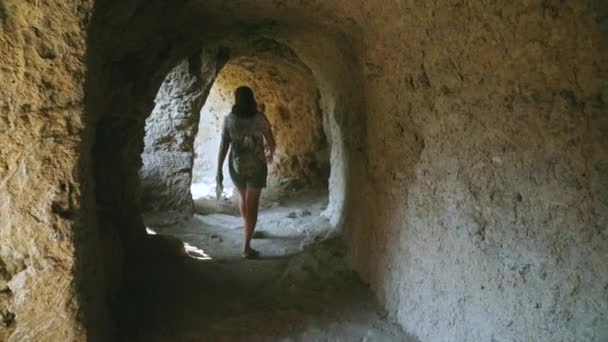 Turista femenina adulta está caminando sola dentro de la cueva con columnas. Movimiento lento — Vídeos de Stock