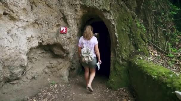 Adulto turista feminino está andando sozinho dentro da caverna com colunas. Movimento lento — Vídeo de Stock