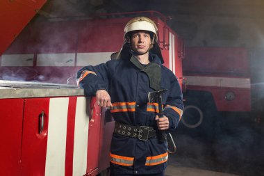 İtfaiyeci (itfaiye) eylem daimi bir firetruck yakınındaki. Acil durum Emanet. Koruma, tehlikeden kurtarmak.