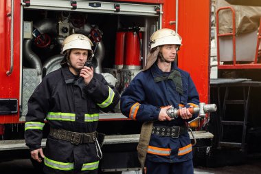 İtfaiyeci (itfaiye) eylem daimi bir firetruck yakınındaki. Acil durum Emanet. Koruma, tehlikeden kurtarmak.