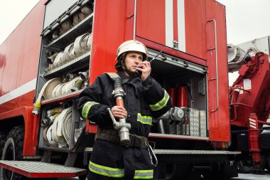 İtfaiyeci (itfaiye) eylem daimi bir firetruck yakınındaki. Acil durum Emanet. Koruma, tehlikeden kurtarmak.