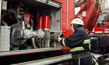 İtfaiyeci (itfaiye) eylem daimi bir firetruck yakınındaki. Acil durum Emanet. Koruma, tehlikeden kurtarmak.