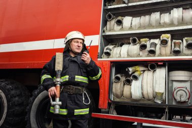 İtfaiyeci (itfaiye) eylem daimi bir firetruck yakınındaki. Acil durum Emanet. Koruma, tehlikeden kurtarmak.