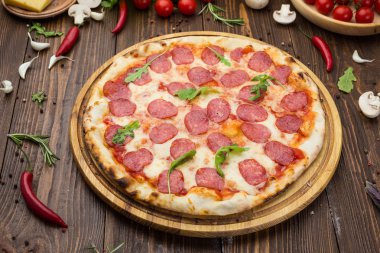 Mozzarella peyniri, salam ve roka ahşap zemin üzerine biberli pizza
