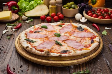 Ahşap arka plan üzerinde güzel İtalyan pizza jambon ve fesleğen yaprakları