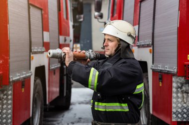 İtfaiyeci (itfaiye) eylem daimi bir firetruck yakınındaki. Acil durum Emanet. Koruma, tehlikeden kurtarmak.