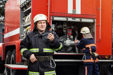 İtfaiyeci (itfaiye) eylem daimi bir firetruck yakınındaki. Acil durum Emanet. Koruma, tehlikeden kurtarmak.