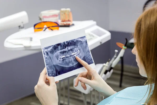 Dentist explaining the details of a x-ray teeth picture to his patient in clinic