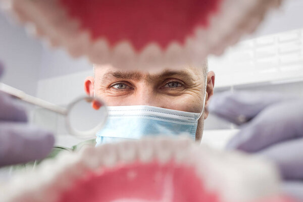 Стоматолог у открытого рта пациента, смотрит в зубы. Оральный уход. Внутренний обет
