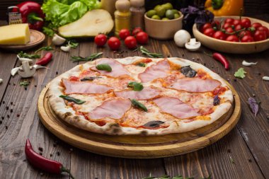 Ahşap arka plan üzerinde güzel İtalyan pizza jambon ve fesleğen yaprakları