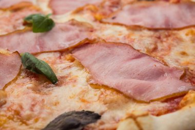 Ahşap arka plan üzerinde güzel İtalyan pizza jambon ve fesleğen yaprakları