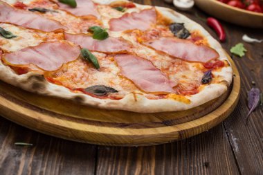 Ahşap arka plan üzerinde güzel İtalyan pizza jambon ve fesleğen yaprakları