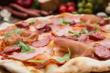 Lezzetli İtalyan pizza jambon, Bavyera sosis ve fesleğen tarafından dekore edilmiş prosciutto ile ahşap arka plan üzerinde bırakır