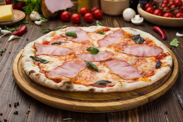 Ahşap arka plan üzerinde güzel İtalyan pizza jambon ve fesleğen yaprakları