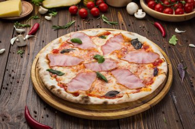 Ahşap arka plan üzerinde güzel İtalyan pizza jambon ve fesleğen yaprakları