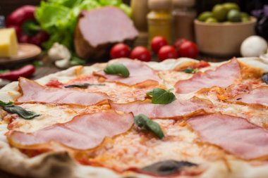 Ahşap arka plan üzerinde güzel İtalyan pizza jambon ve fesleğen yaprakları