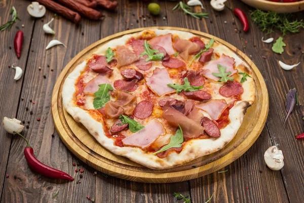 Lezzetli İtalyan pizza jambon, Bavyera sosis ve fesleğen tarafından dekore edilmiş prosciutto ile ahşap arka plan üzerinde bırakır