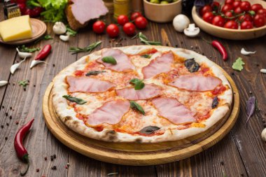 Ahşap arka plan üzerinde güzel İtalyan pizza jambon ve fesleğen yaprakları