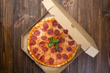 Mozzarella peyniri, salam ve roka kutusunda ahşap zemin üzerine biberli pizza