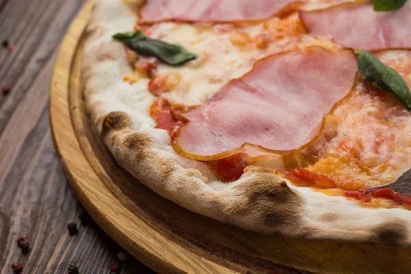 Ahşap arka plan üzerinde güzel İtalyan pizza jambon ve fesleğen yaprakları