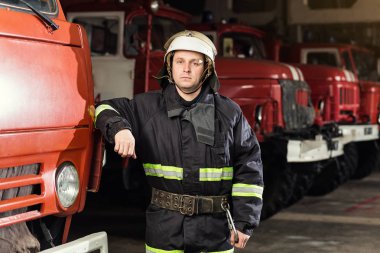 İtfaiyeci (itfaiye) eylem daimi bir firetruck yakınındaki. Acil durum Emanet. Koruma, tehlikeden kurtarmak.