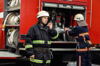 İtfaiyeci (itfaiye) eylem daimi bir firetruck yakınındaki. Acil durum Emanet. Koruma, tehlikeden kurtarmak.