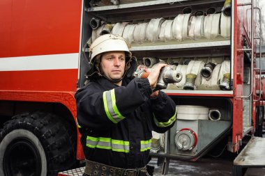 İtfaiyeci (itfaiye) eylem daimi bir firetruck yakınındaki. Acil durum Emanet. Koruma, tehlikeden kurtarmak.